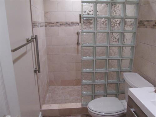 Custom tile shower with glass-block wall for light and privacy — a timeless remodel built for function and style by Lucius Complete Home.
