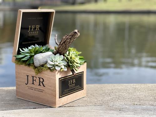 A stunning flower arrangement that exudes a touch of masculinity, presented in a charming wooden cigar box.