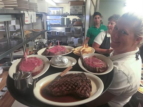 Server holding tray of 4 steak dinners