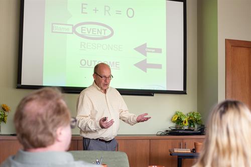 man presenting an equation in a conference room
