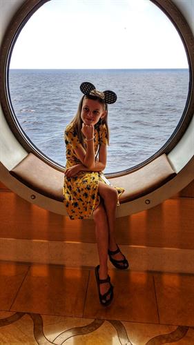 Child posing in front of porthole on cruise