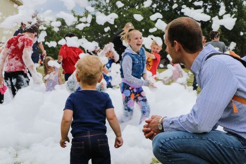 Dad and son with girl in background with bubbles at Party in the Park 2019