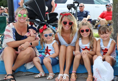 Women and kids with sunglasses smiling at parade
