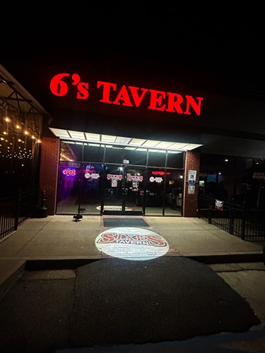 Logo Light projecting Sixes Tavern Logo outside on their sidewalk