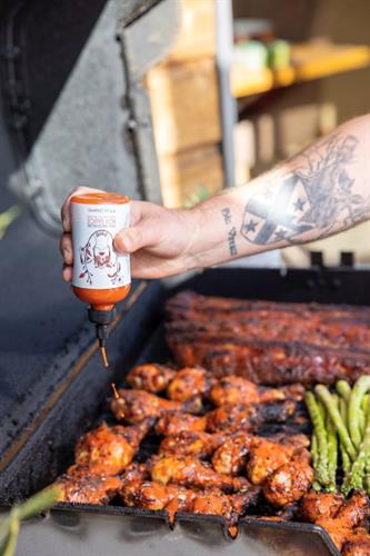 hot sauce being poured onto grilled chicken on a grill - Product photography hot sauce being poured onto grilled chicken on a grill - Product photography