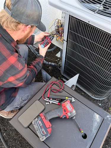 All Around Cooling & Heating technician diagnosing an air-conditioning condenser.
