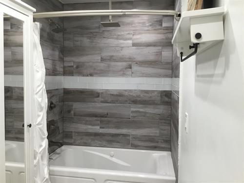 Wood grain shower tile with rain shower and jacuzzi tub