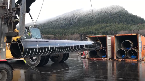 Large diameter pipe being unloaded from 40' containers