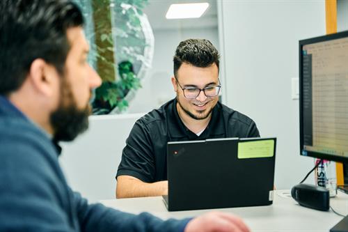 Collaborative workspace: Technician Corey and Engineer Dan engage across desks and screens in our focused office setting.