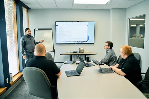 Presenting with clarity—team huddled around the screen, turning ideas into action.