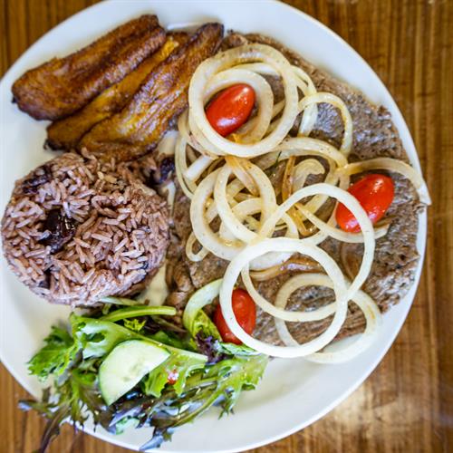 Ropa Vieja Plato -Shredded beef braised with sweet peppers, onions, garlic, tomato, served with congris, Tostones and Side Salad.
