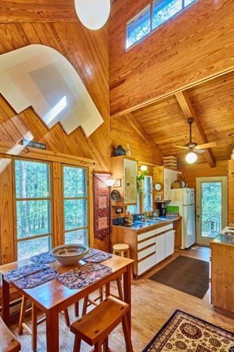 Cabin dining room and kitchen with view of woods and back porch and deck. 