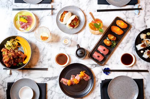 Plated table with sushi, small plates, and cocktails