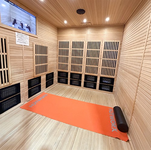 Inside HOTWORX Portsmouth: an infrared workout sauna with a mat, foam roller and instruction screen.