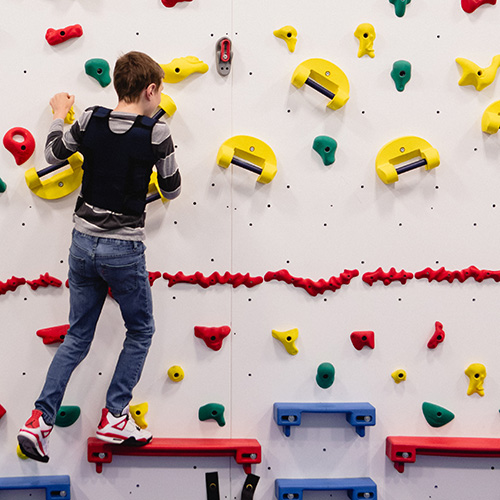 A student uses the climbing wall in Birchtree's school gym.