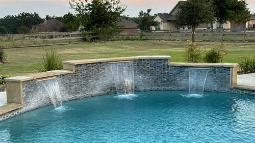 A stunning pool upgrade, transforming a standard design with a elegant curved waterfall feature and custom tilework.