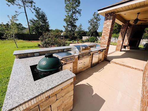 Outdoor kitchen with grill, side burners, smoker, fridge, storage, and wash down station