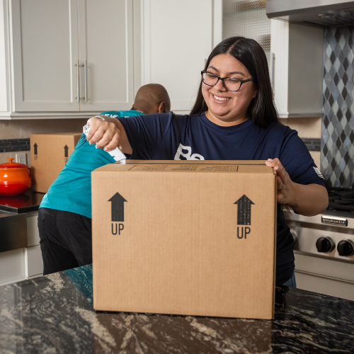 Jasmine seals a box closed after packing