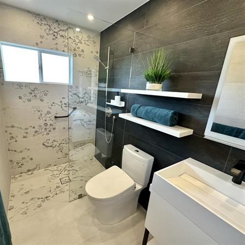 A striking bathroom remodel featuring black tiles contrasted with ivory tiles adorned with delicate floral patterns.