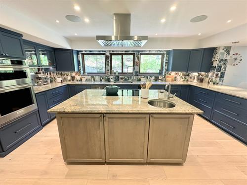 Bright kitchen makeover with light wood cabinets and a playful tropical backsplash.