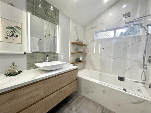 Marble-look tiles with green accents create a sophisticated, lively ambiance