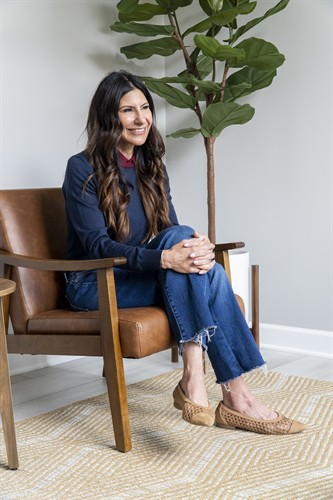 Clinician seated in a brown leather chair inside a calm and bright Chicago therapy office.