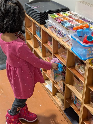 A preschool student selecting hands-on learning materials in the Quantum STEM School classroom.