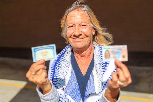 Client Dana beams happily with her new Social Security card and ID. She can now obtain disability benefits for her MS.