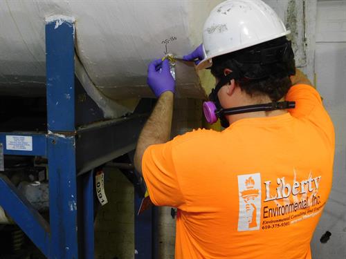 A licensed professional from Liberty Environmental collects a sample as part of an asbestos containing materials survey. 