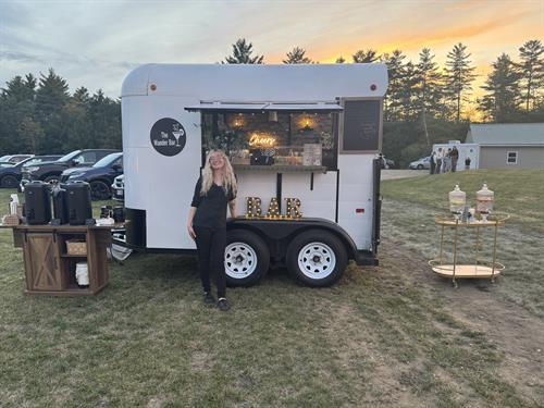 Wedding bartender stands in front of Vintage Horse Trailer Bar, Hydration Station, and Tea & Coffee Station at wedding bar service in Keene, New Hampshire
