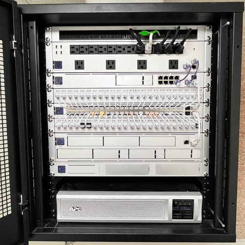Wall-mounted network rack with labeled patch panels, a PoE switch, security camera recorder, and battery backup in El Monte, CA