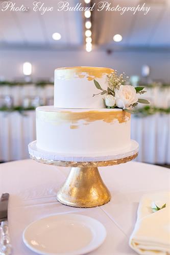 Two-tier cake with edible gold painted edging and burst of white flowers