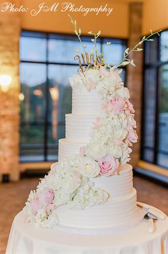 Five-tier cake with horizontal texture buttercream and a cascade of pink and white flowers