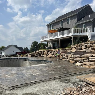 Completed pavers around pool with custom build boulder wall