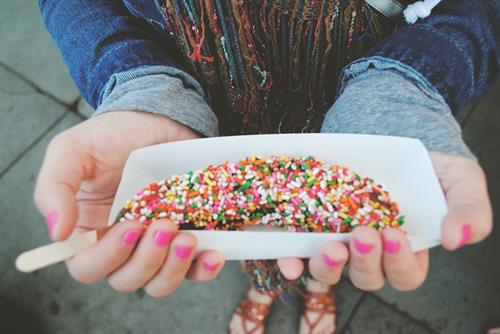 Frozen banana, dipped in milk chocolate and topped with rainbow sprinkles