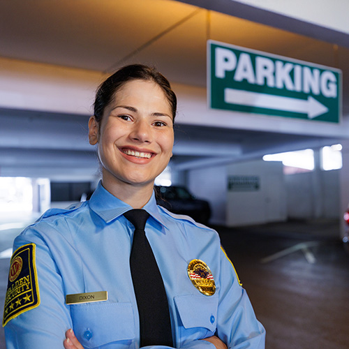 Security officer smiles while patrolling parking deck interior 