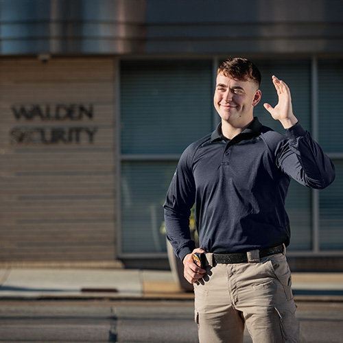 Security Officer smiles and waves at a visitor from his post