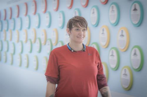An associate smiling in front of a colorful wall.