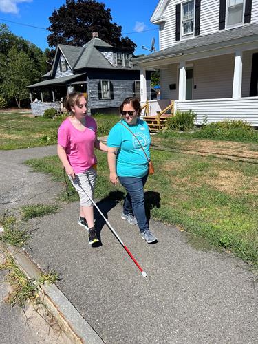 A teen client learning sidewalk safety from a Future In Sight Certified Orientation & Mobility Specialist,