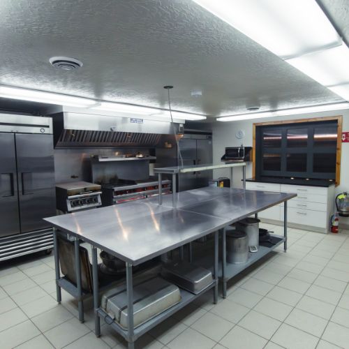 Industrial kitchen, gas stove, grill, griddle, large workspace, 2 industrial fridges, 1 industrial freezer, silverware, plates, bowls, and glassware all available to use.
