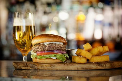 Picanha Burger: Fresh ground in-house, smoked provolone, romaine lettuce, tomato, onion, chimichurri aioli, brioche bun. Served with crispy polenta. 