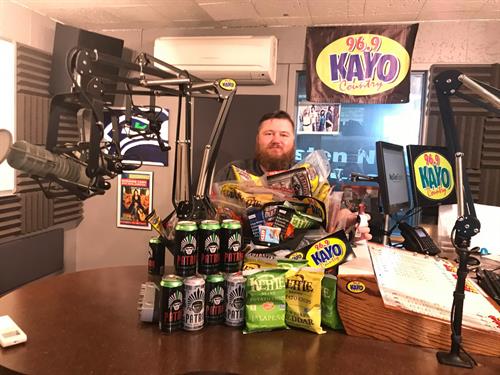 Afternoon Drive Host Nat George showcasing a prize pack of snacks for a Garth Brooks Contest/Promotion