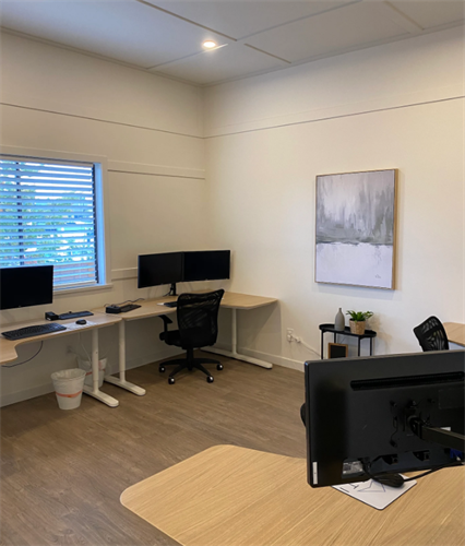  A serene and tidy Cloverdale workspace in a digital marketing office, with sleek monitors and comfortable seating, complemented by a tranquil abstract painting — a harmonious setting for creative thought and strategic planning.