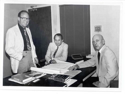 Crest Industries founder, Tucker Robison (right), sitting at his desk with coworkers.