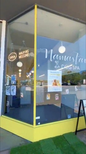 Bright and welcoming storefront of Namast’ay Dog Spa in San Mateo, CA, featuring large glass windows framed in cheerful yellow and a glowing “Open – Walk-Ins Welcome” sign. This local dog grooming spa offers professional pet care, gentle grooming, and a relaxing environment for dogs of all breeds. Located conveniently in the San Mateo business district, Namast’ay Dog Spa is known for its clean, modern design and friendly service that keeps Bay Area pets looking and feeling their best.