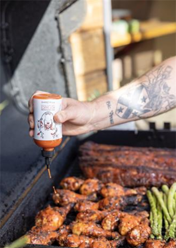 hot sauce being poured onto grilled chicken on a grill - Product photography 