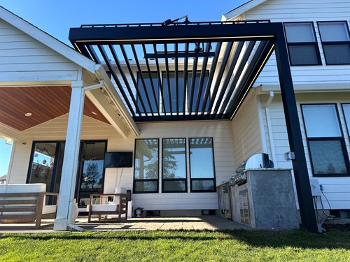 An adjustable louvered pergola brings flexible shade to this outdoor gathering space.