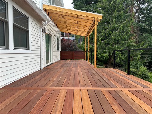 Batu hardwood decking, a cedar pergola, and cable railing create a warm, open backyard setting.