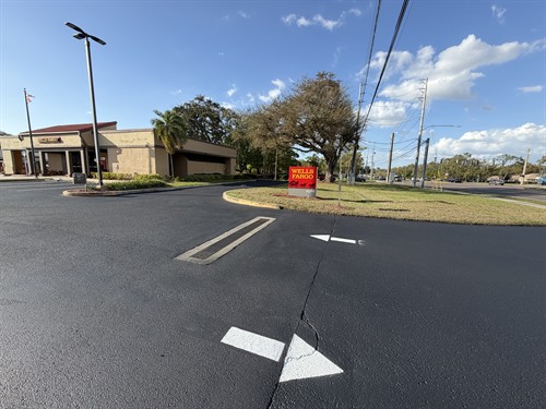 Fresh sealcoating with directional arrows at Wells Fargo parking lot entrance in Clearwater