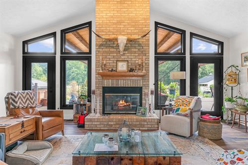 A stunning after-shot of a living room in Pinckney, MI, featuring newly installed black Soft-Lite windows. These modern, custom-shaped replacement windows, including large fixed panes and operable units, perfectly frame the outdoor views and enhance the vaulted ceiling. As Energy Star windows, they significantly boost the home's efficiency and aesthetic, surpassing standard Home Depot windows in both style and performance.